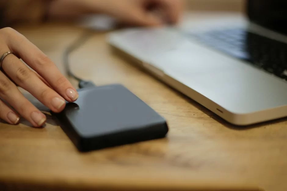 An image of an external HDD and laptop, showing how to back up AVI video files