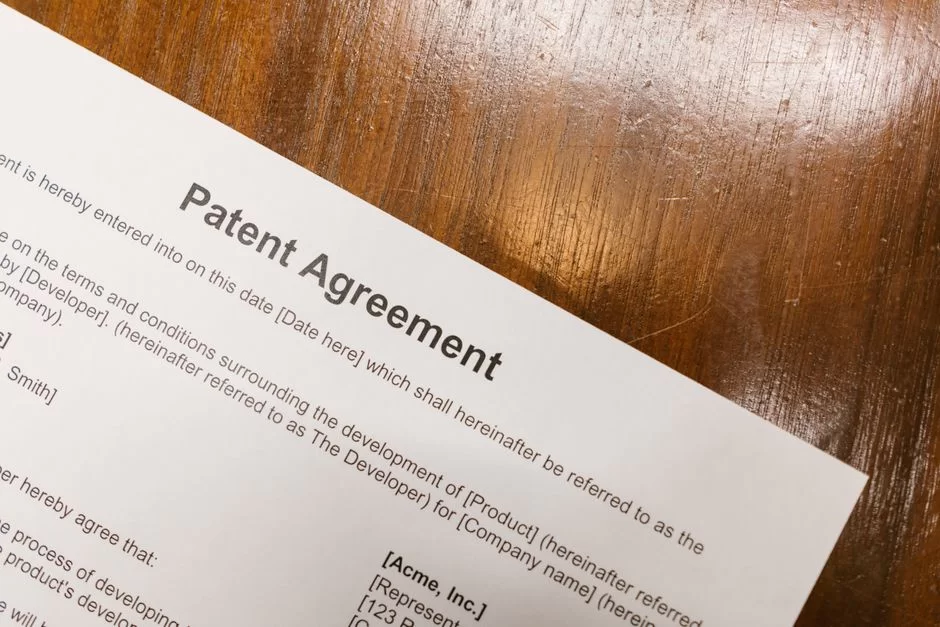 Bir masada duran yazılım patent belgeleri, lisans anlaşmaları ve bir kalem, codec teknolojilerinin yasal yönlerini ve fikri mülkiyetini vurguluyor