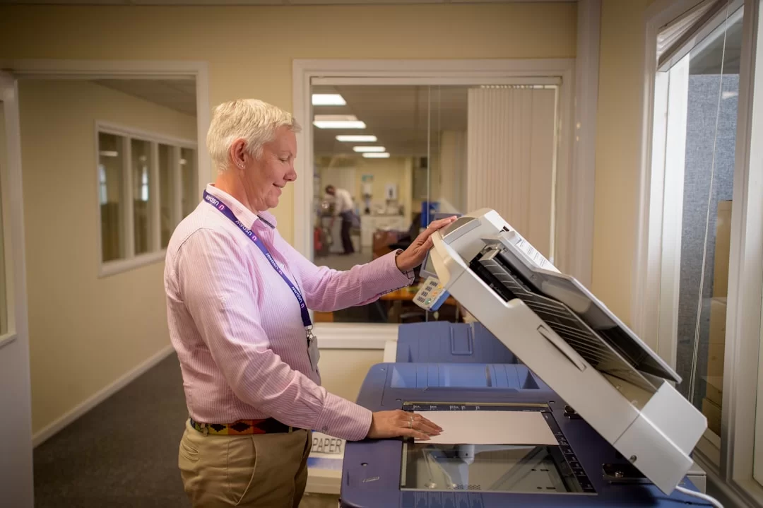A user placing A4 paper into a photocopier