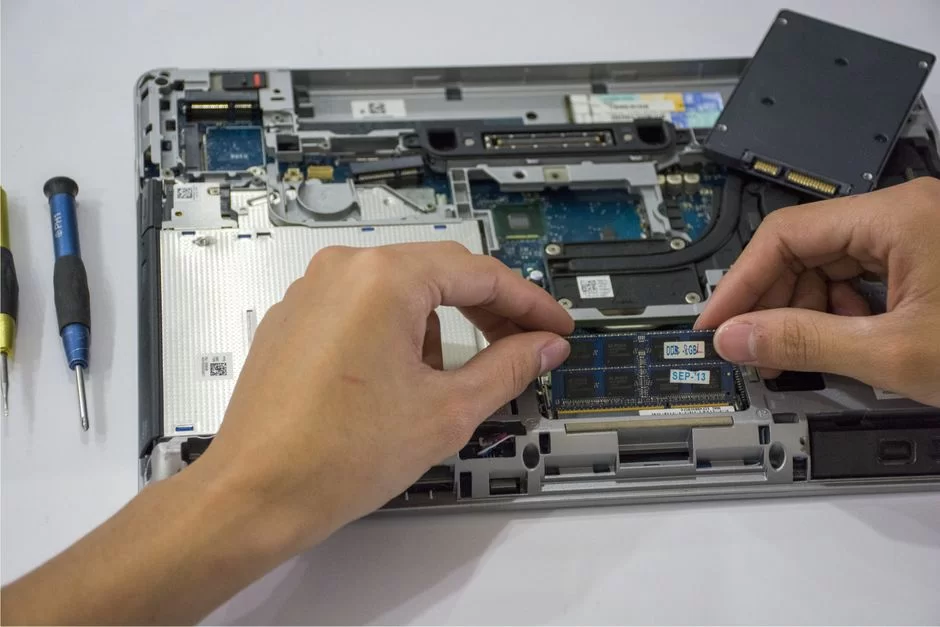 User installing RAM modules into a laptop
